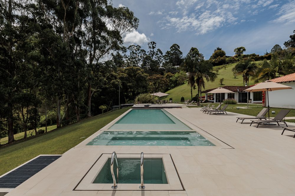 The cold plunge pool set into the deck at the end of the lap pool, with the lawns and houses behind