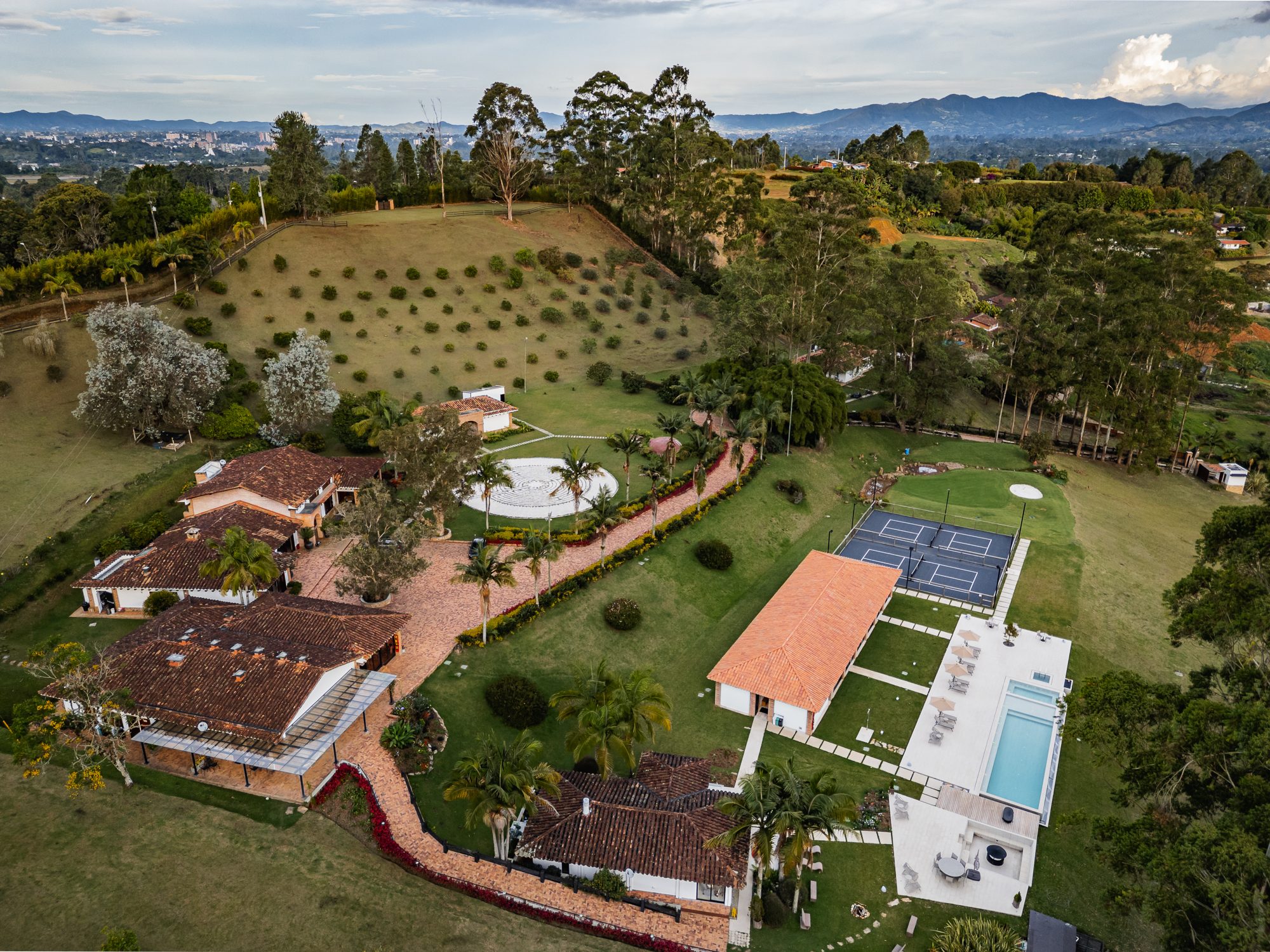 The Mountains of Hope property seen from the air: houses, pool, courts, gardens and the stone labyrinth, with the Rionegro valley beyond