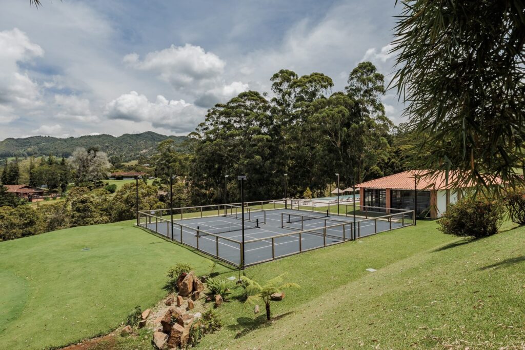 Enclosed padel and sports courts set into the lawn, surrounded by trees and open grass