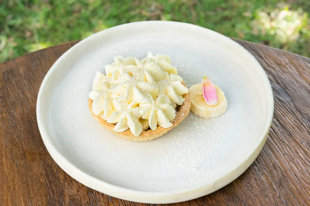 A creamy pasta dish on a white plate, finished with an edible flower