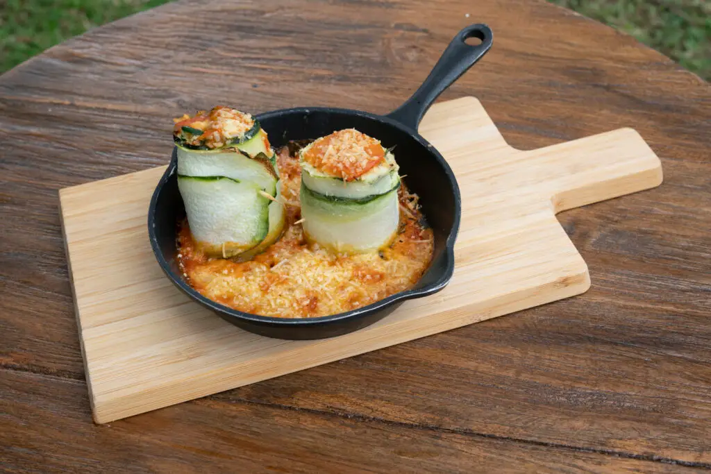 Courgette rolls served in a small cast-iron skillet on a wooden board