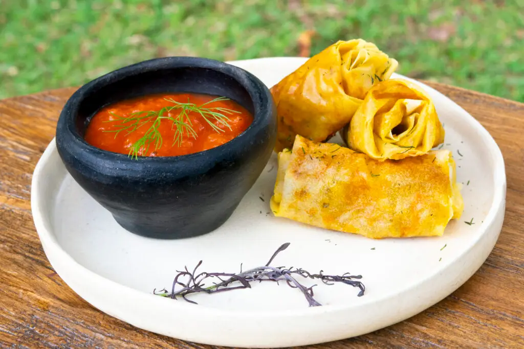 Tomato soup in a stone bowl beside folded corn pancakes