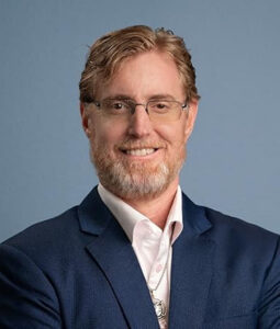 Dr. Bryan Ardis, CEO of Ardis Labs and host of The Dr. Ardis Show, in a navy jacket against a grey backdrop