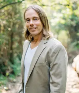 Dr. Edward Group, founder of Global Healing, photographed outdoors in a pale jacket against green foliage