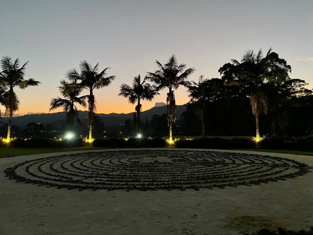 The stone labyrinth at dusk, with the palms lit behind it