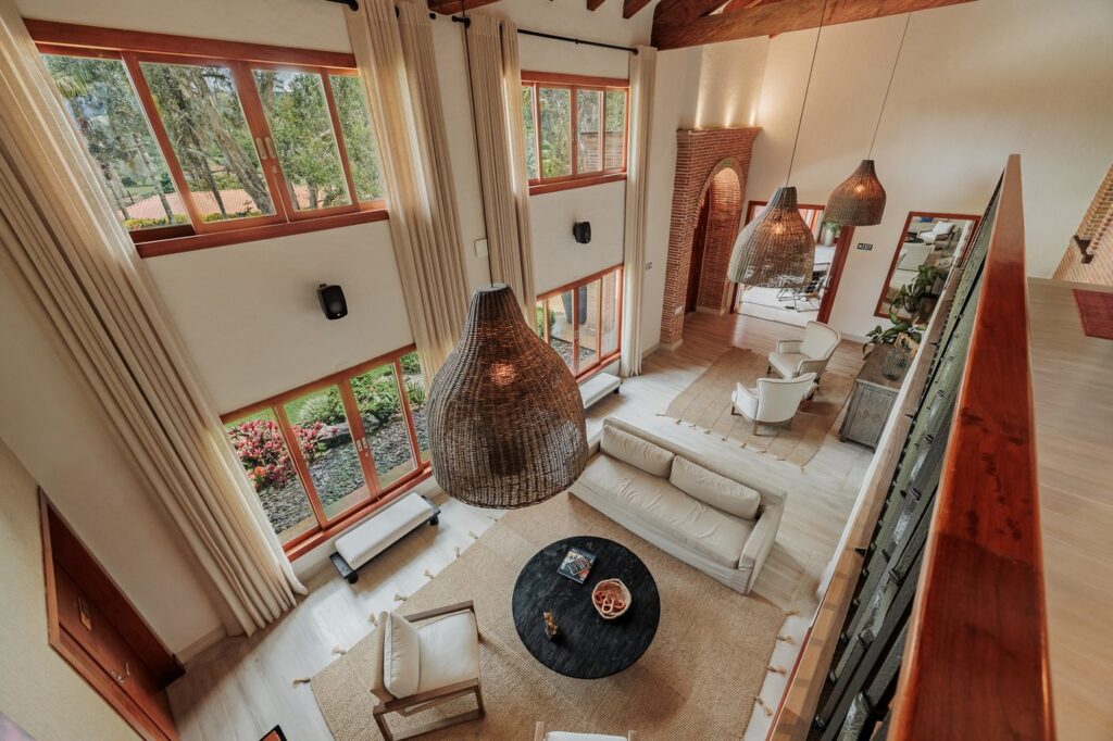 The presidential suite, a tall open room with a wall of windows, seating area and woven pendant lamps